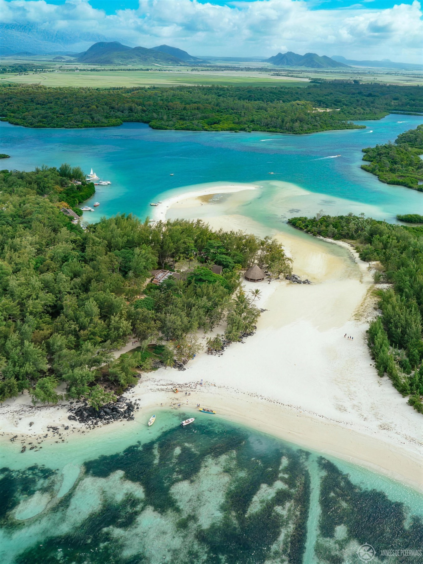An aerial view of a turquoise lagoon and white-sand beach fringed by mountains, Mauritius