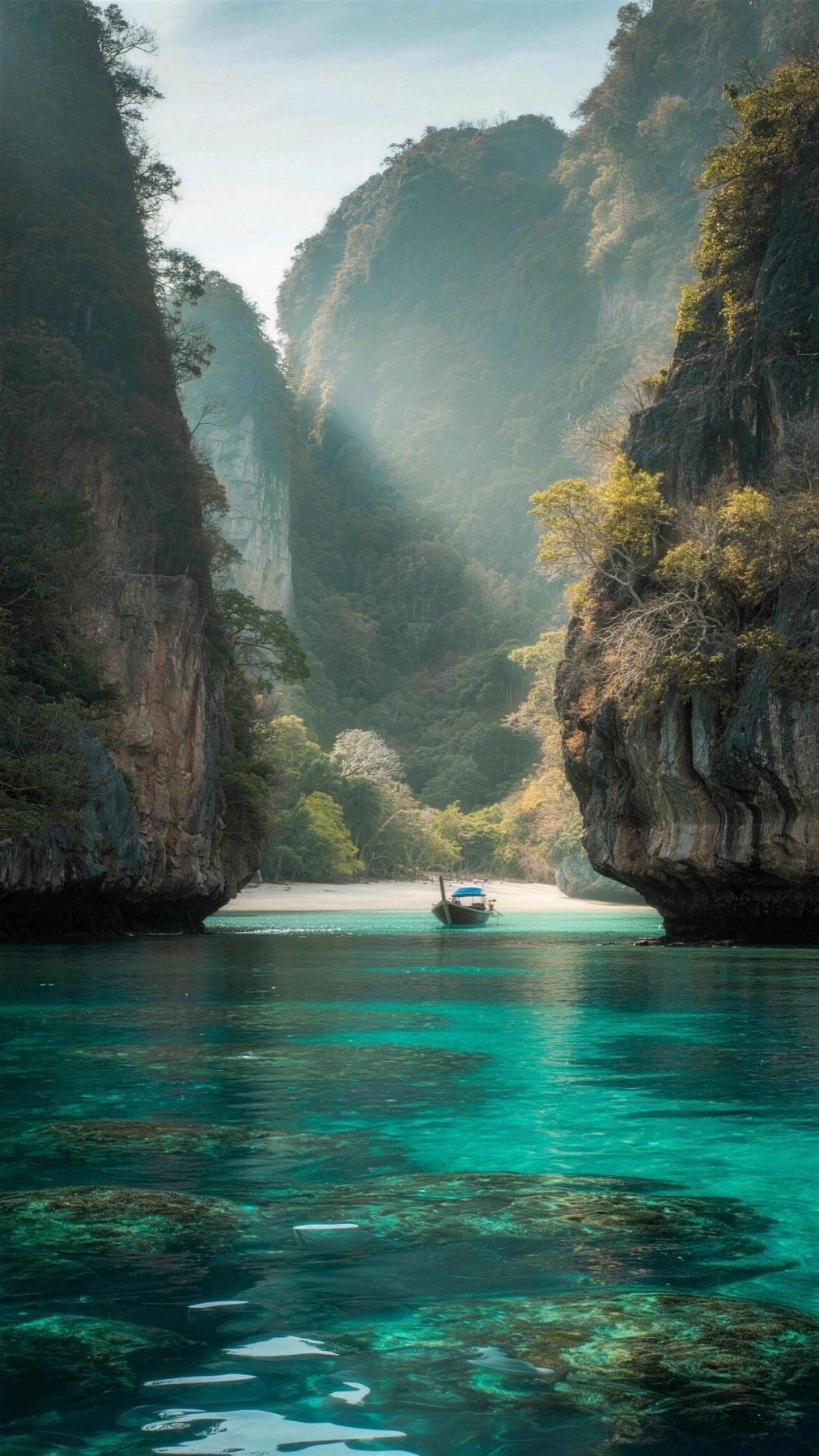 A longtail boat in a turquoise lagoon between limestone cliffs, Thailand